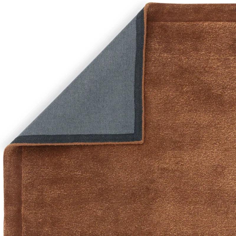 Close-up of brown rug with non-slip backing, corner folded to reveal underside texture