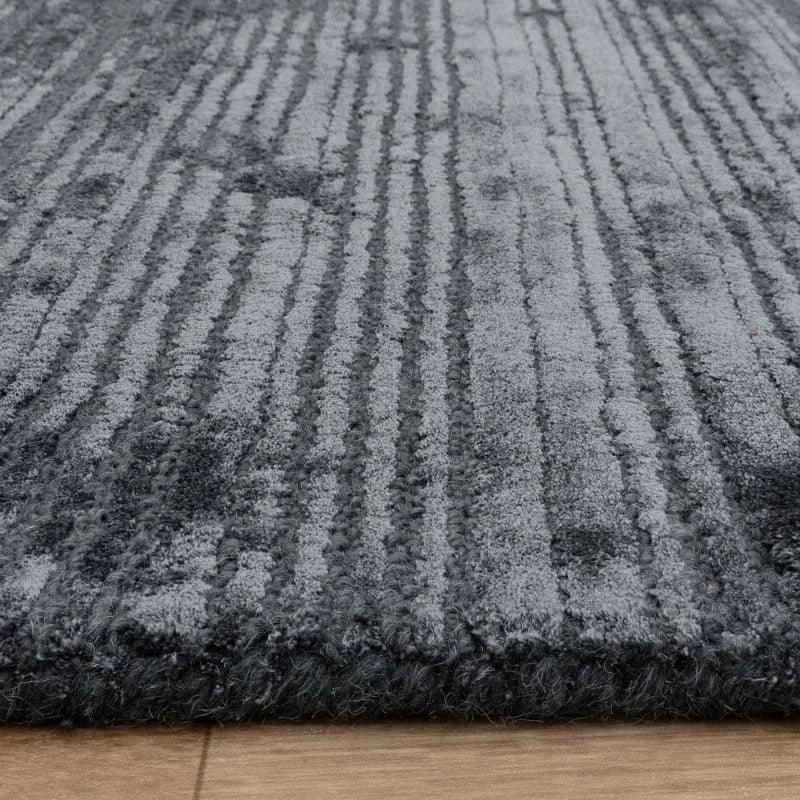 Textured grey area rug with raised striped pattern on wooden floor