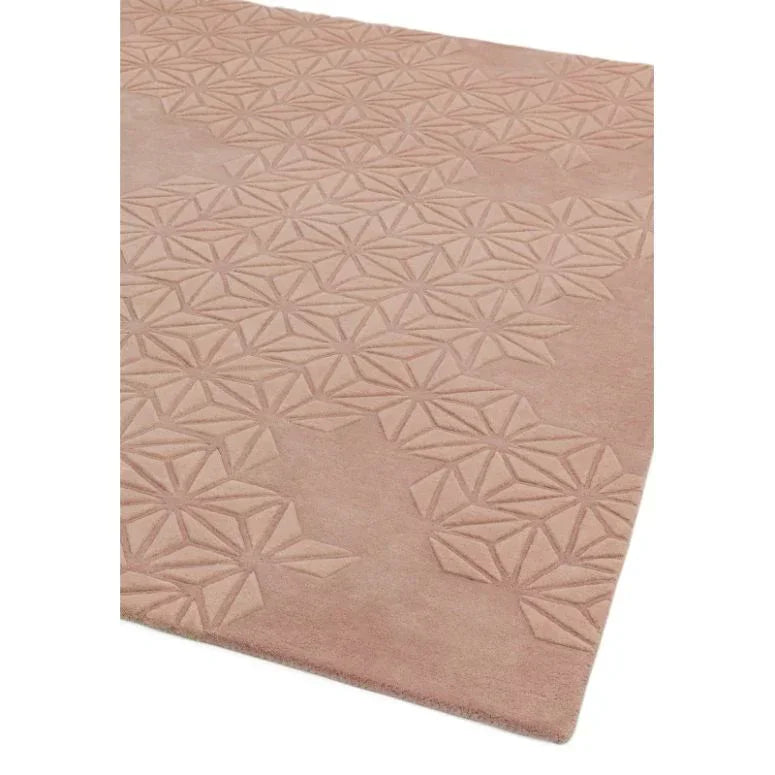 Blush pink geometric pattern area rug with carved texture, corner view