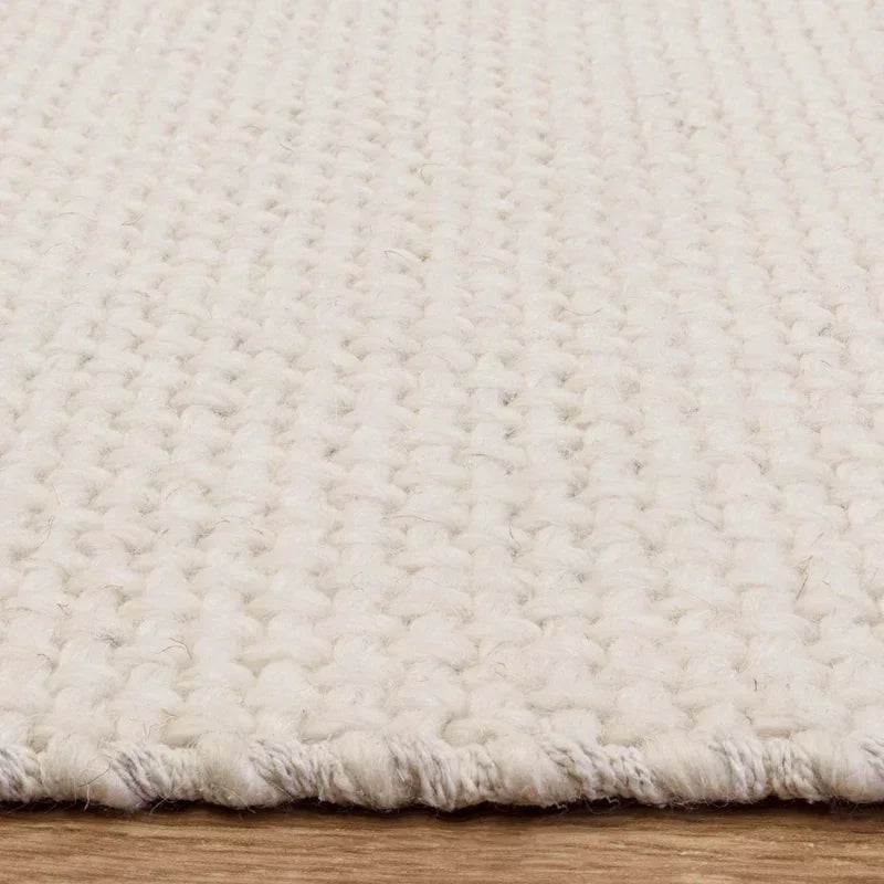 Close-up of cream wool rug with chunky weave on wooden floor