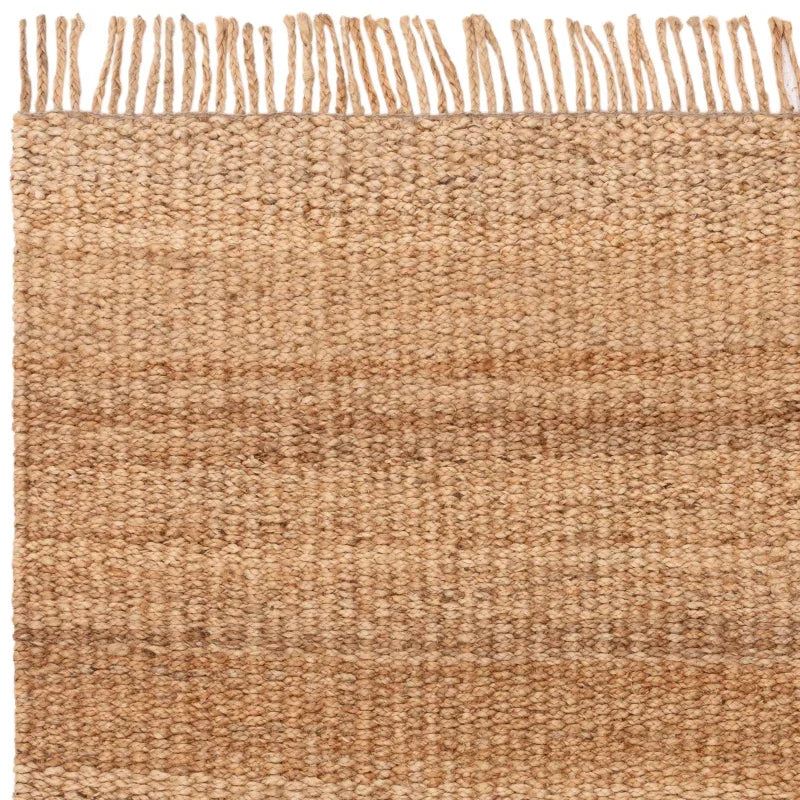 Natural jute rug with woven texture and fringe edge, close-up view