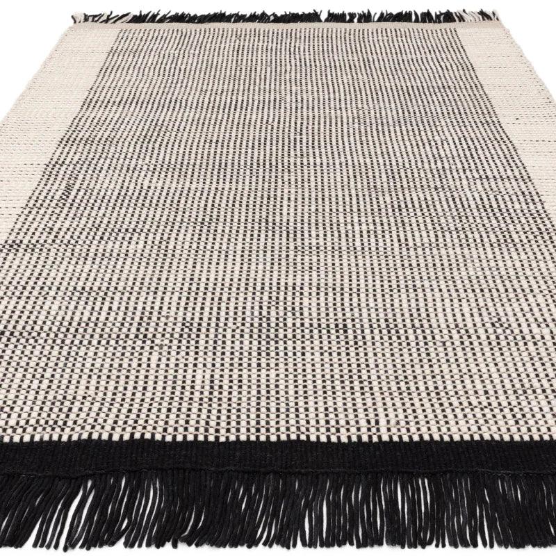 Black and white woven rug with fringe edging and bordered pattern