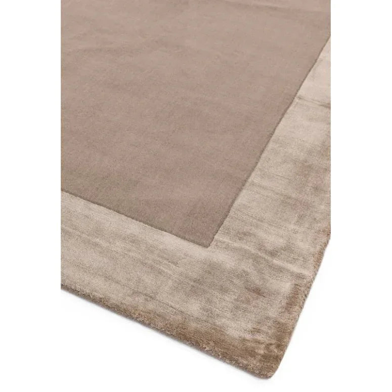 Rectangular beige area rug with wide textured border and soft pile