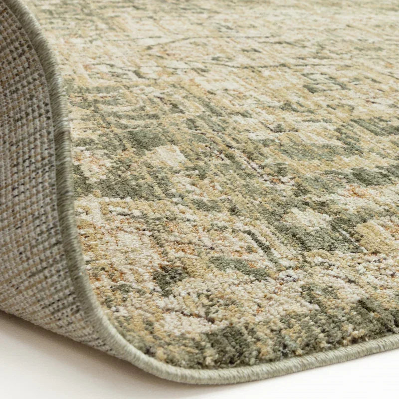 Close-up of patterned area rug with green and beige tones, showing detailed edge finish