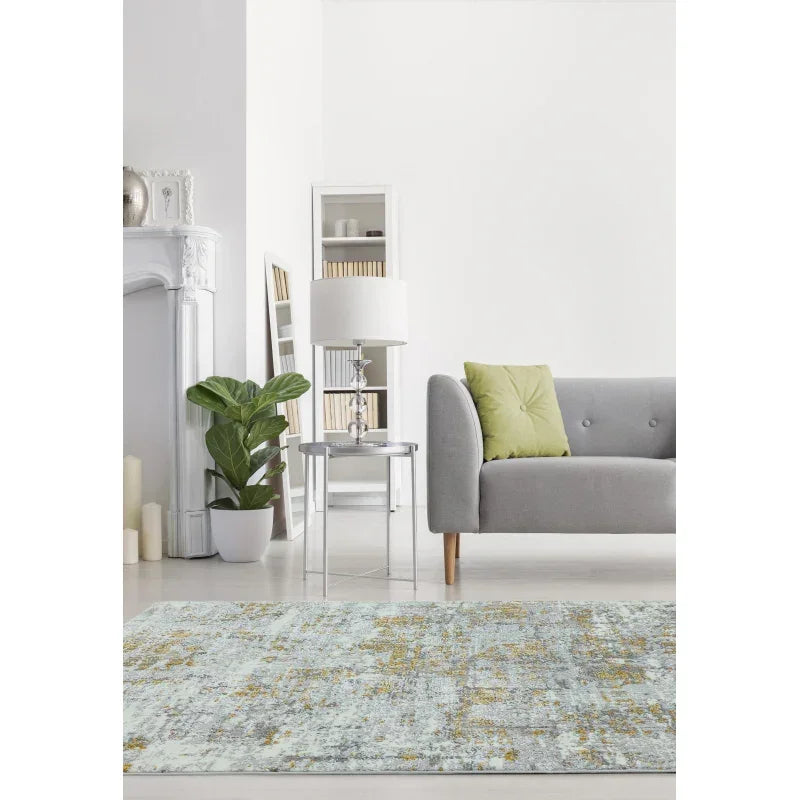 Modern living room with grey sofa, green cushion, patterned area rug and indoor plant