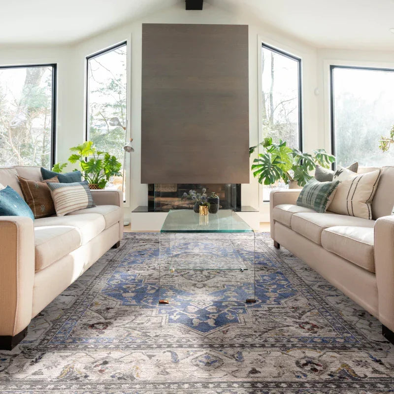 Beige sofas with patterned cushions facing glass coffee table on blue Persian style rug