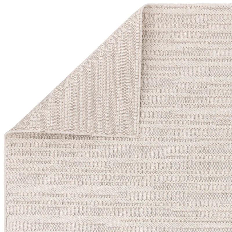 Beige woven area rug with subtle stripe pattern and folded corner detail