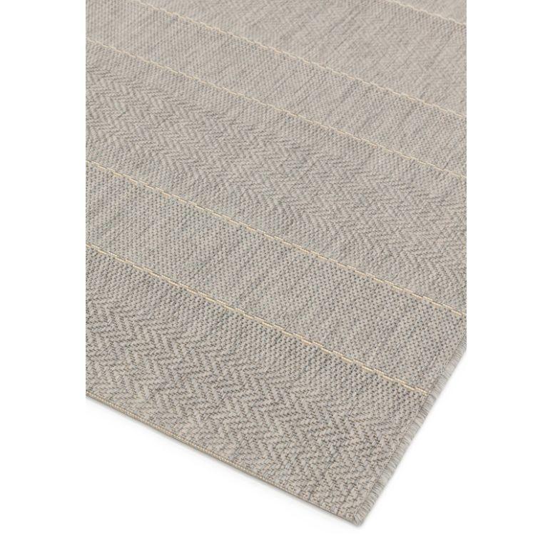 Beige woven rug with subtle chevron pattern and stitched detailing, corner close-up view