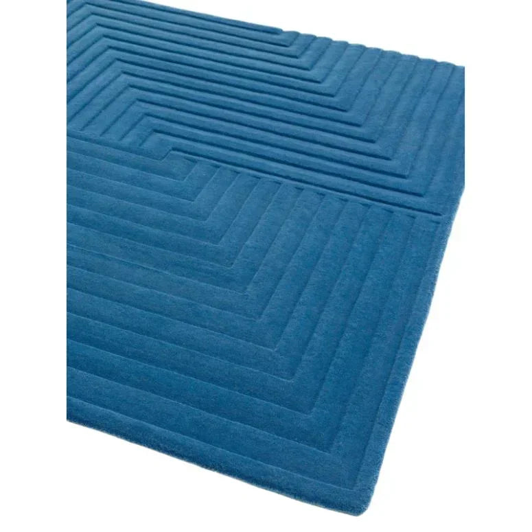 Blue geometric rug with raised pattern and corner view on white background