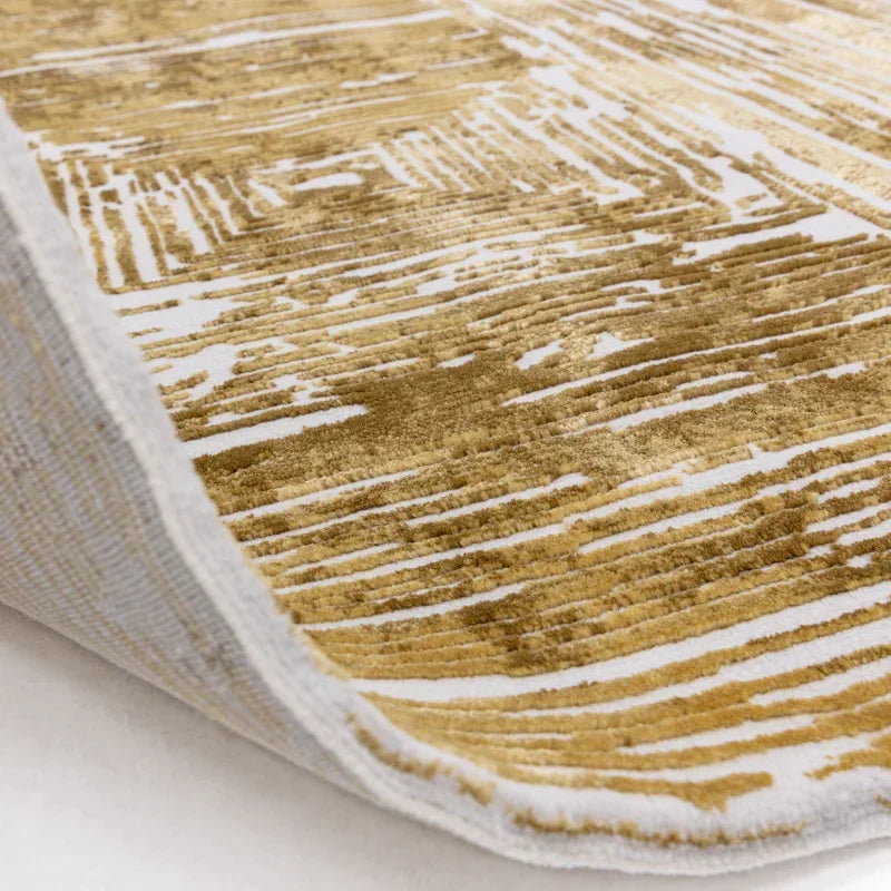 Modern gold and cream area rug with abstract linear pattern, corner flipped up