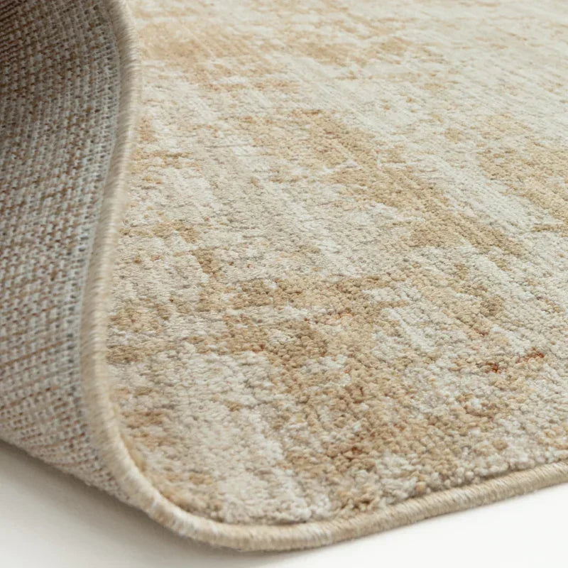 Beige area rug with textured pattern and stitched edge, close-up of rug corner