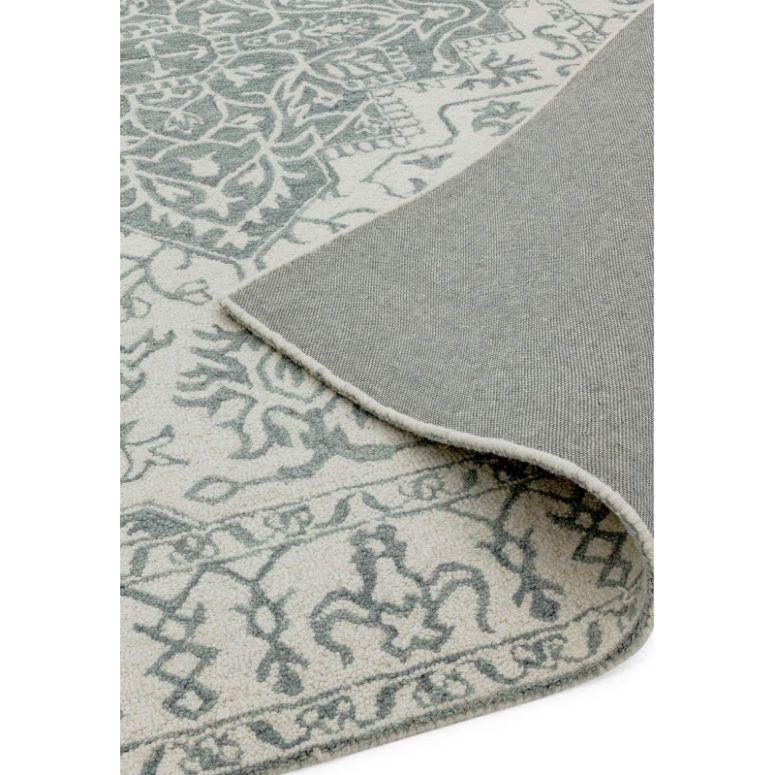 Grey and white patterned area rug with corner flipped to show backing