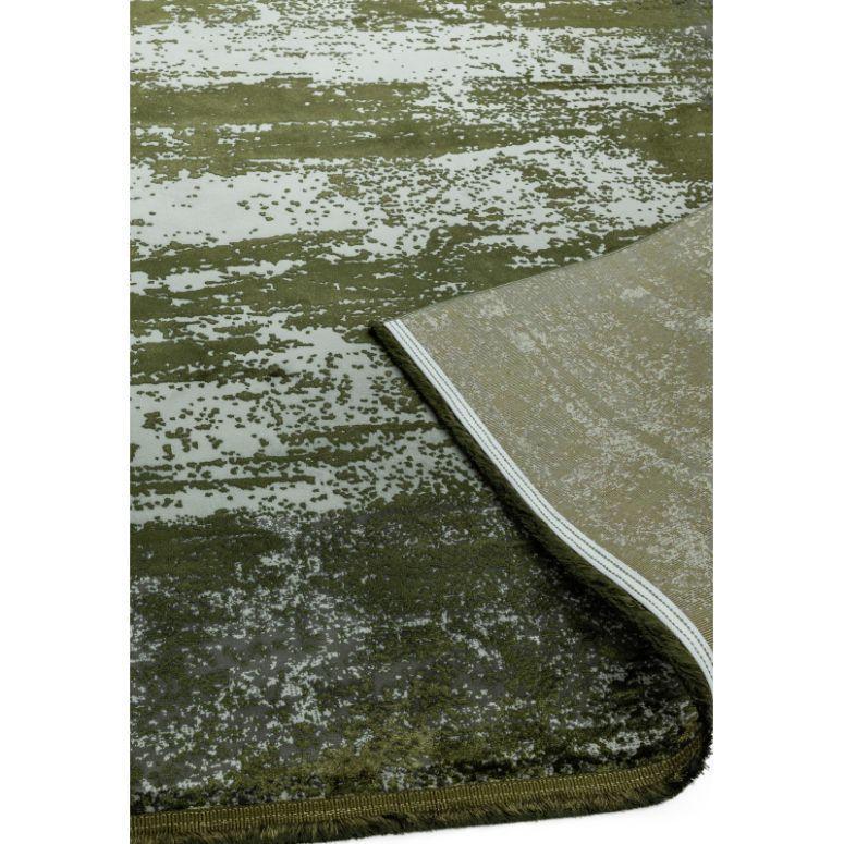 Green patterned area rug with textured detail and corner folded to show backing