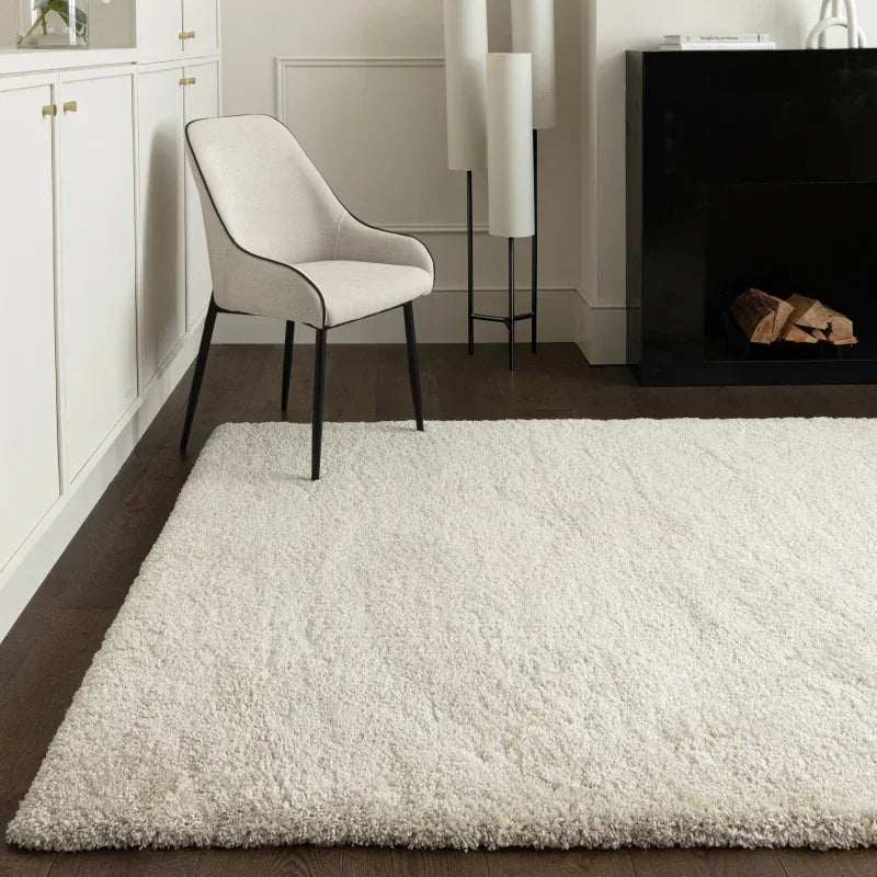 Cream shaggy rug on dark wood floor beside modern accent chair and fireplace