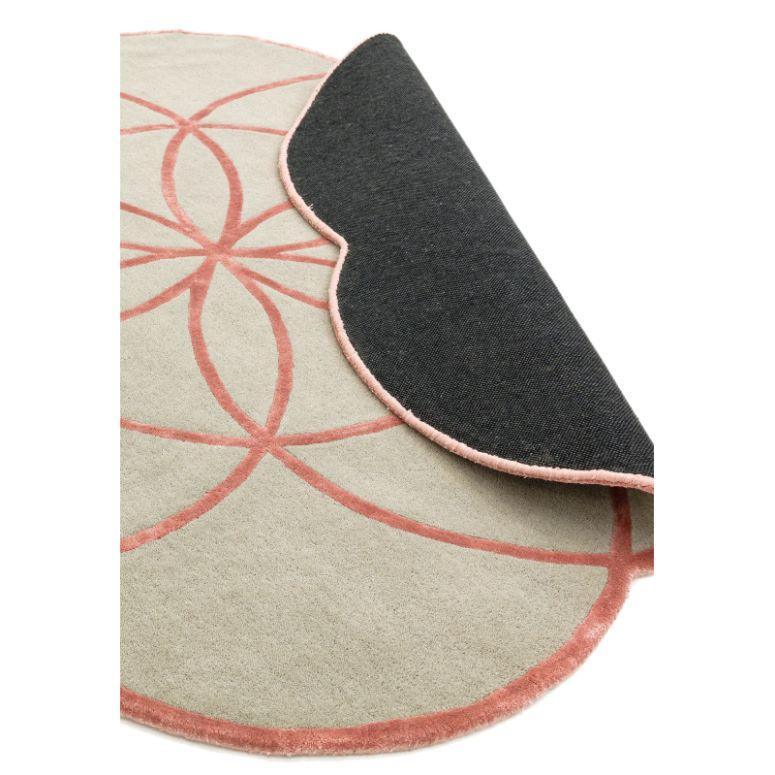 Round beige and pink rug with geometric pattern, partial underside visible