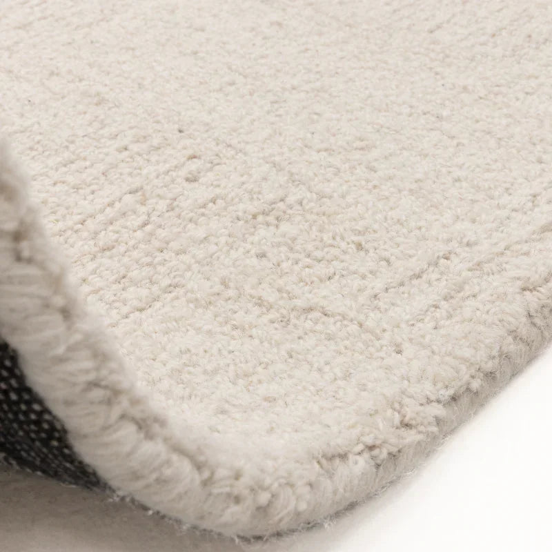 Close-up of cream textured rug corner showing soft pile and woven fabric backing