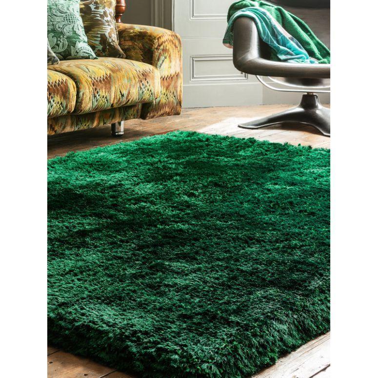 Green shaggy rug on wooden floor in living room with patterned sofa and modern chair