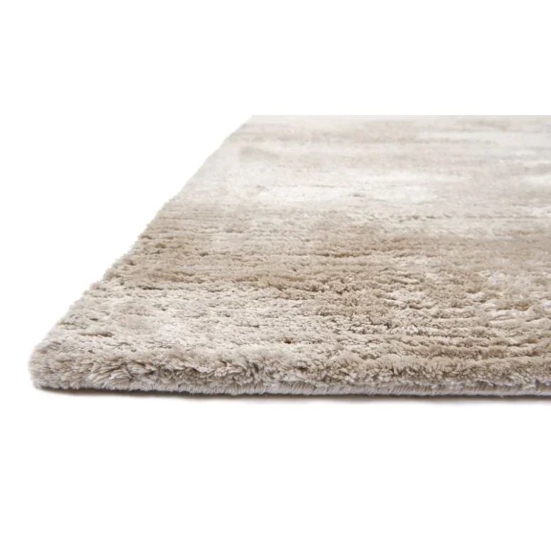 Beige shaggy rug with thick pile, close-up side view on white background