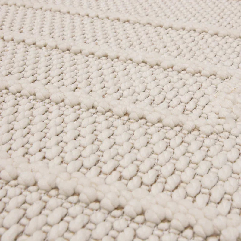 Closeup of cream wool rug surface with textured woven pattern