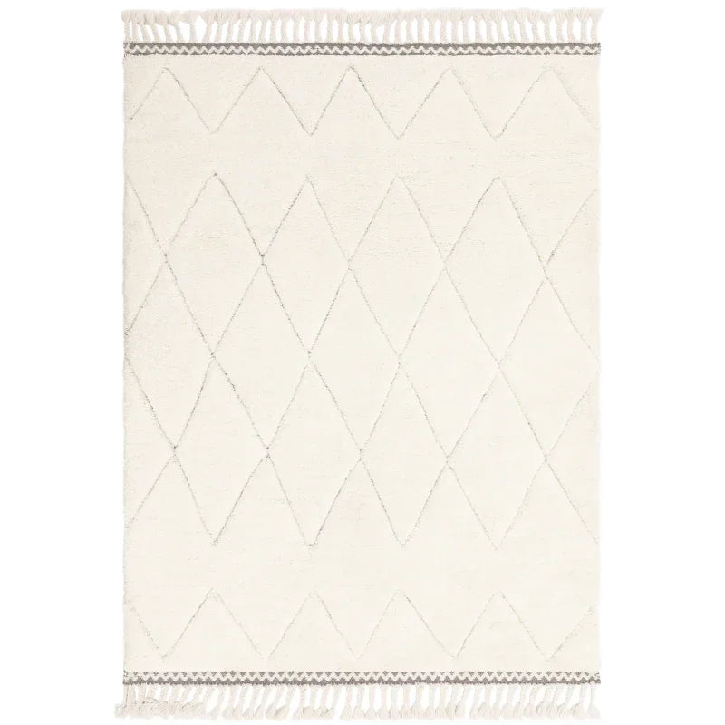 Cream area rug with diamond pattern and tassel fringe edges, shown from above