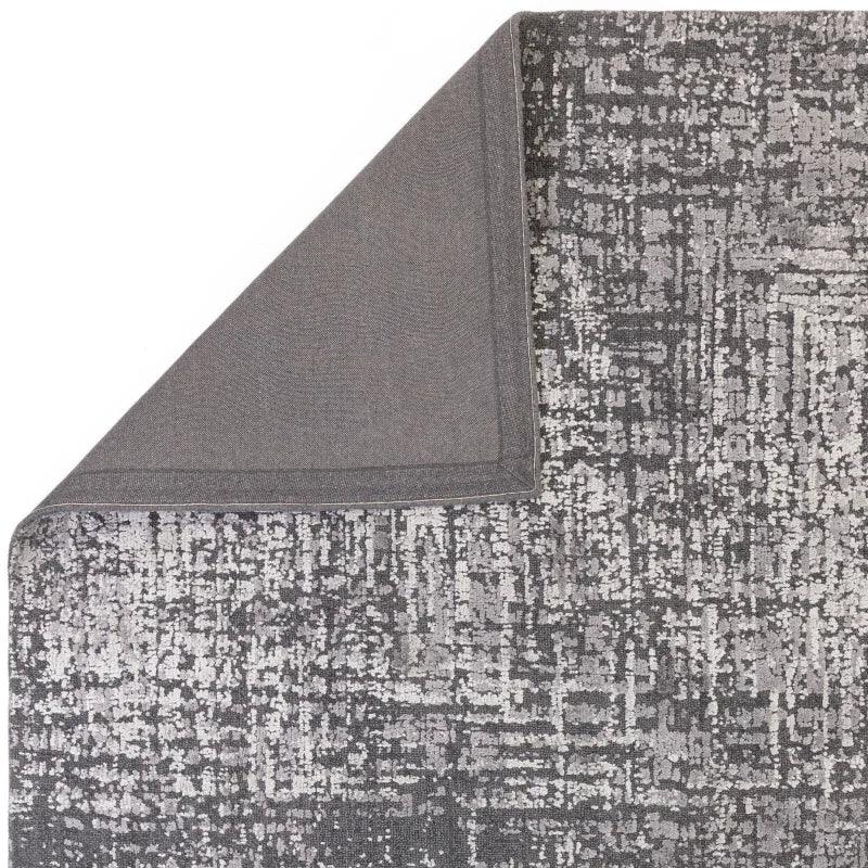 Modern grey area rug with abstract pattern and corner flipped to show backing