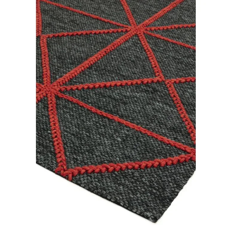 Dark grey rug with red geometric stitched pattern, close-up of corner detail