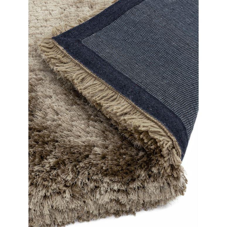 Closeup of beige shaggy rug with textured pile and woven backing