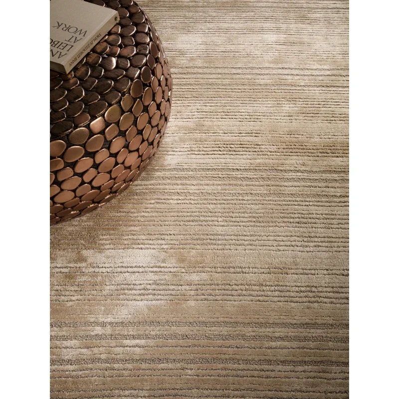 Beige textured rug with subtle stripes and bronze circular decor table in living room setting