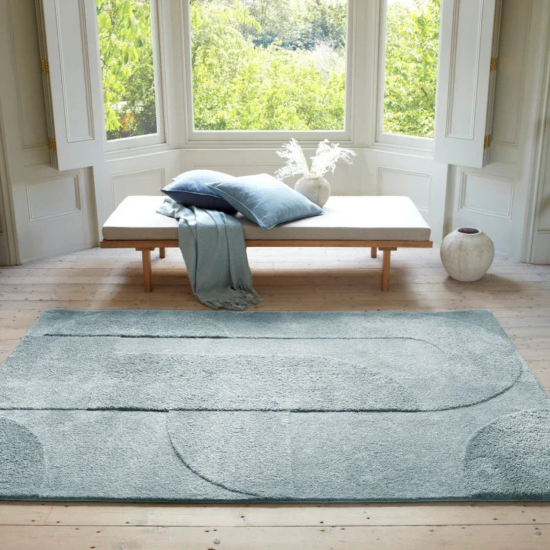 Light blue area rug with geometric pattern in bright living room with wooden floors