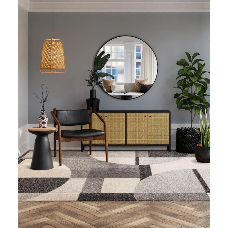 Modern living room features textured sideboard, black chair, indoor plants and round wall mirror