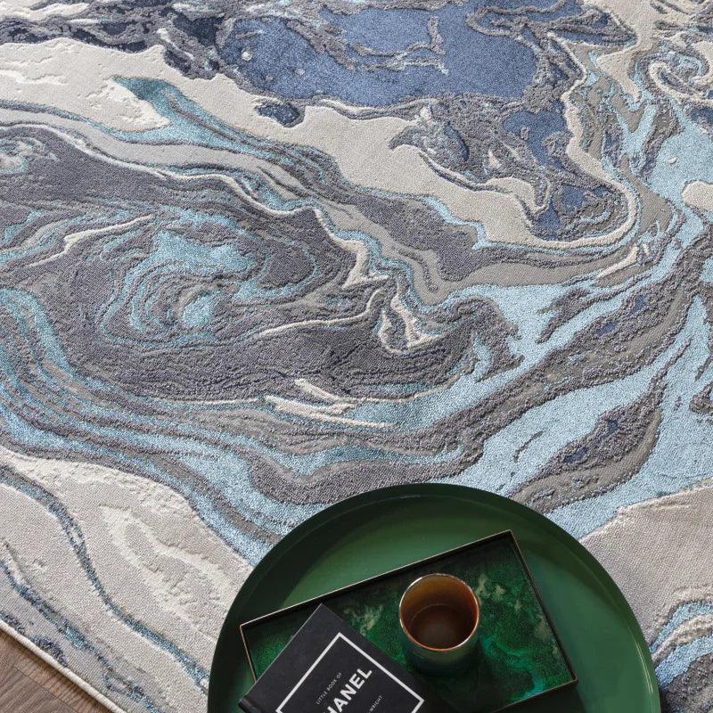 Abstract blue and grey area rug with swirling pattern beside a green tray and cup