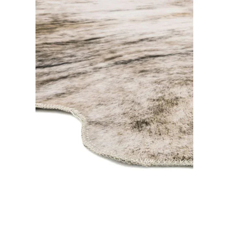 Close-up of natural cowhide rug in beige and brown tones with stitched edge detail