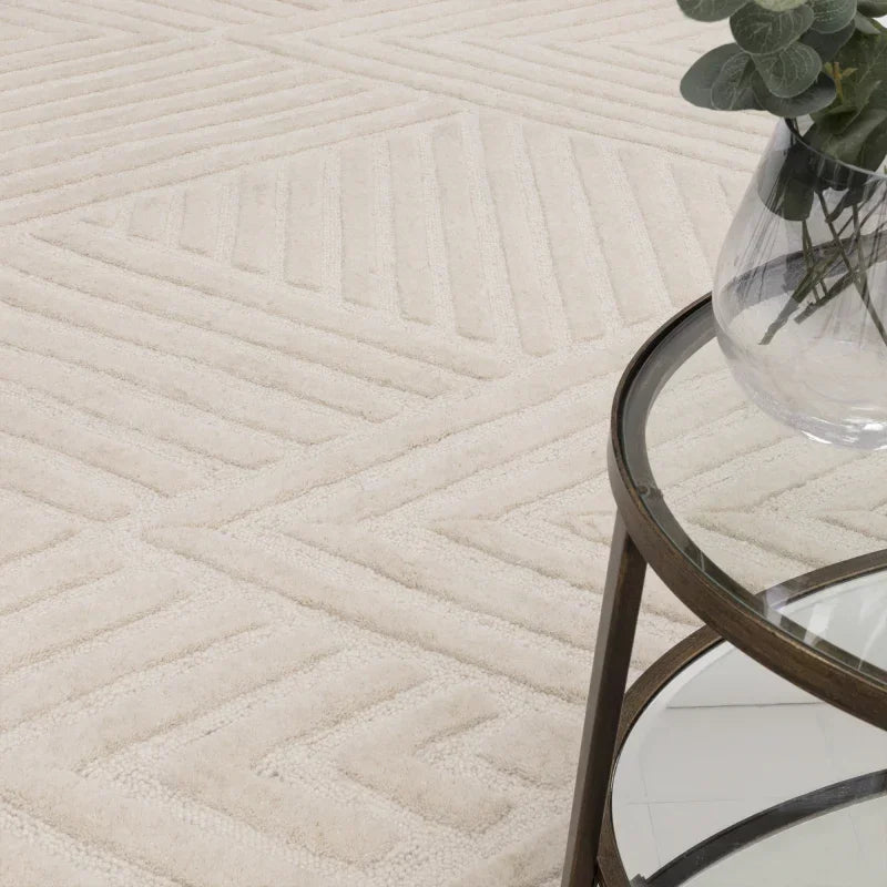 Cream geometric pattern rug with glass top side table and eucalyptus in vase