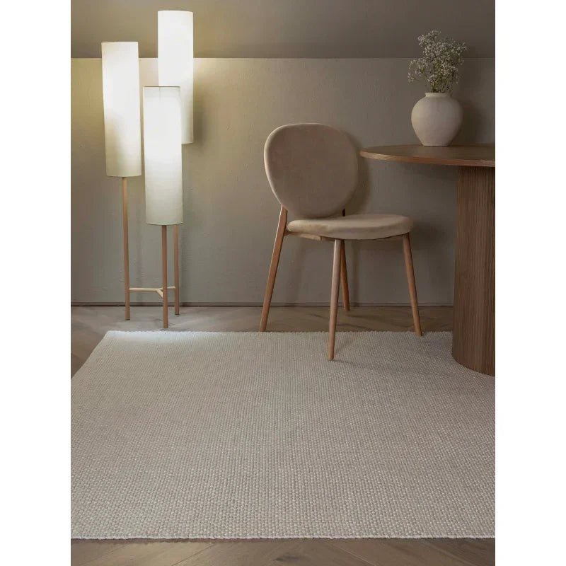 Cream textured area rug in modern living room with beige chair and wooden table