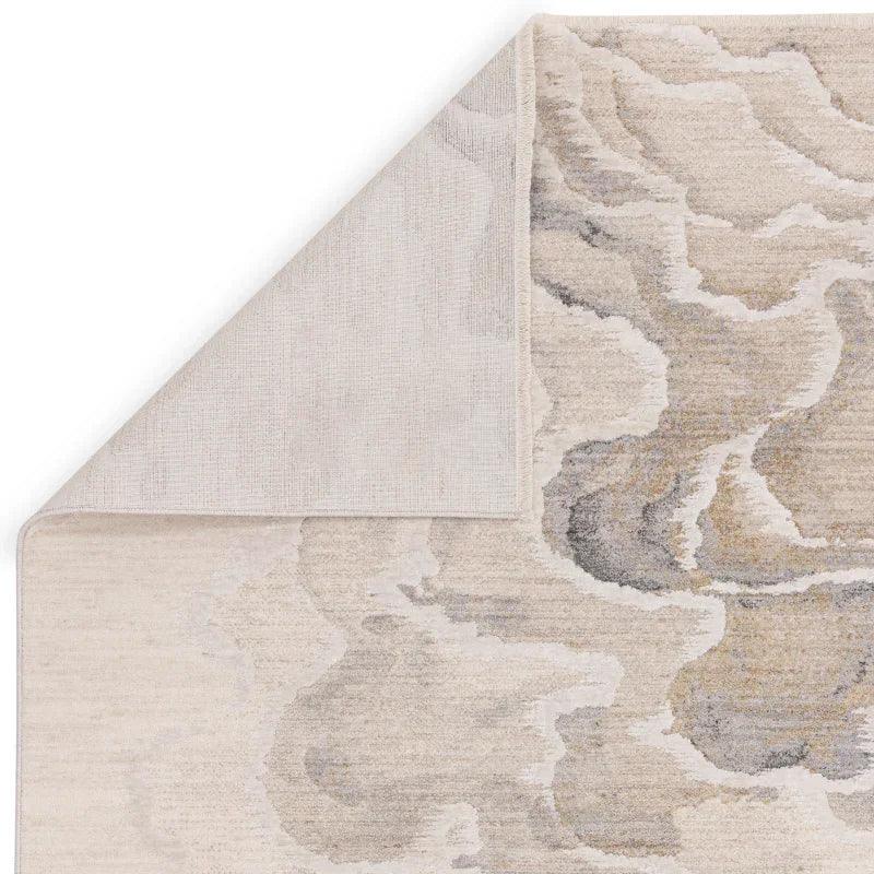 Beige abstract pattern area rug with one corner flipped to show backing detail