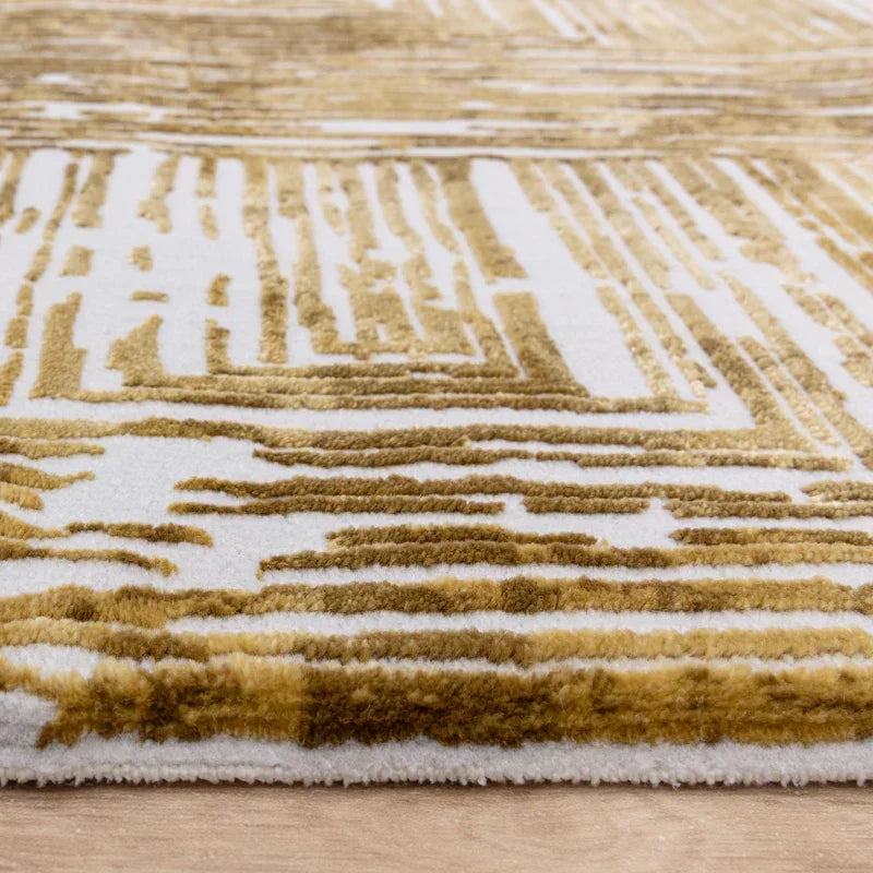 Closeup of gold and white modern area rug with textured geometric pattern on wooden floor
