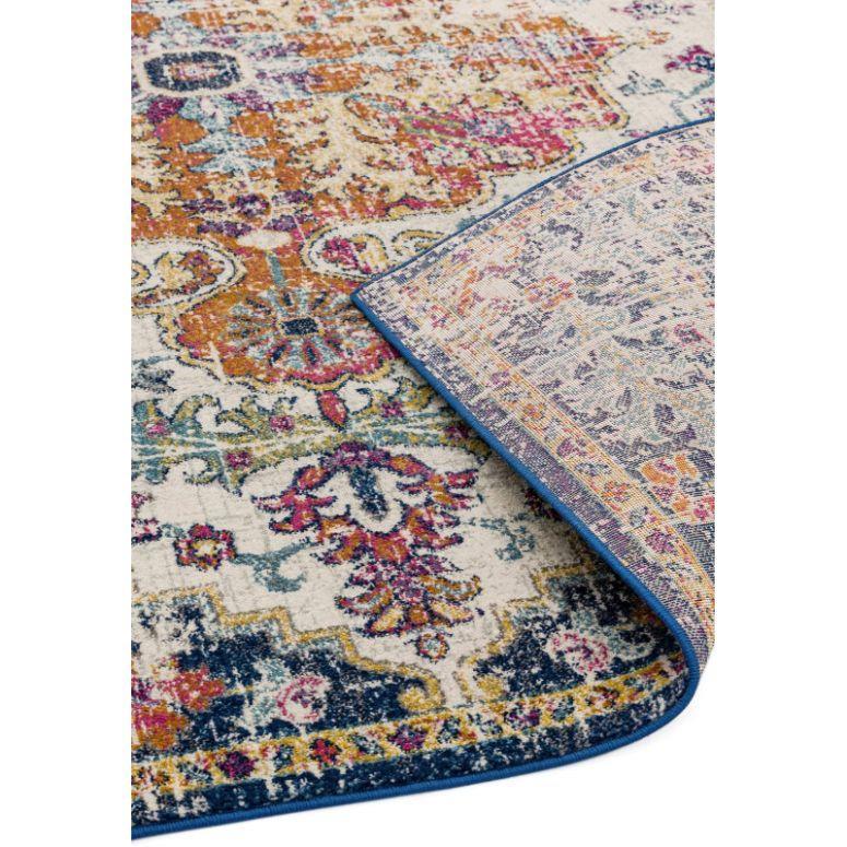 Multicolored area rug with vintage floral pattern and blue border, corner flipped to show backing