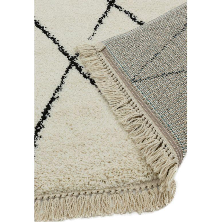 cream area rug with black diamond pattern and fringed edge, close-up of texture and backing