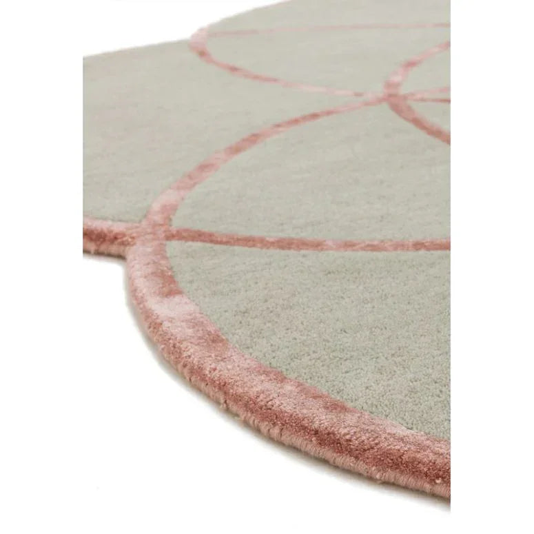 Close up of round area rug with light grey surface and pink geometric border detail
