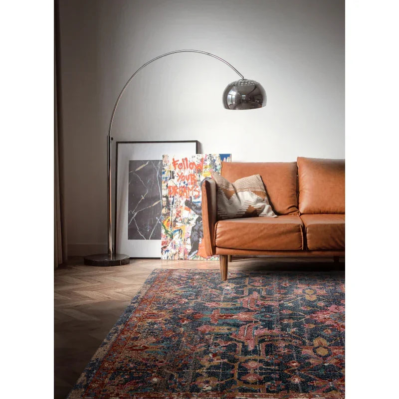 Brown leather sofa with scatter cushion, patterned rug, floor lamp and wall art in living room