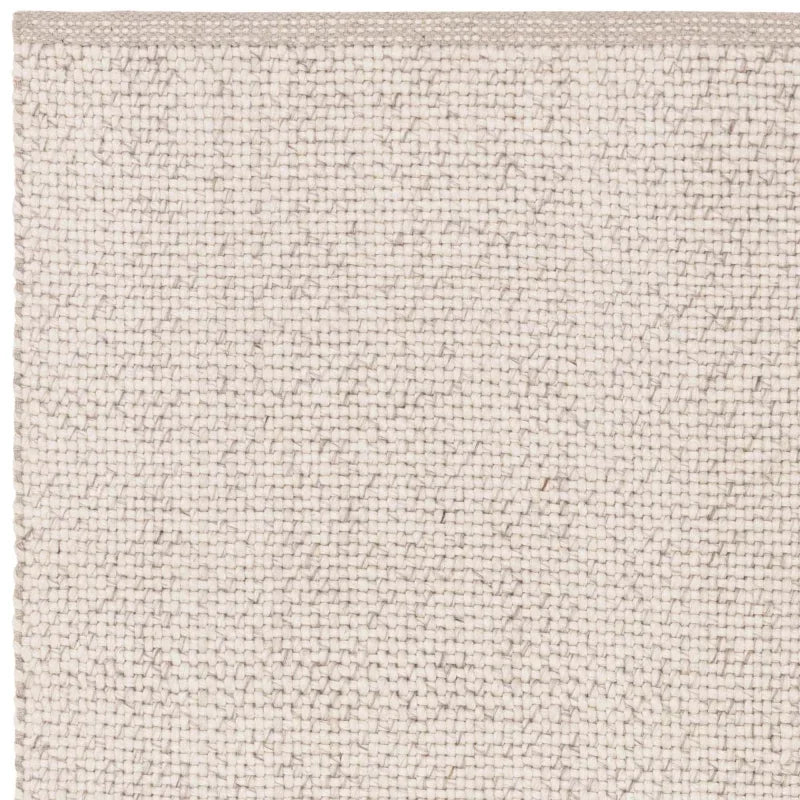 Close-up of cream woven rug texture showing edge and tight weave detail