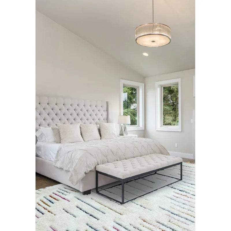 White upholstered bed with tufted headboard and bench in modern bedroom with windows