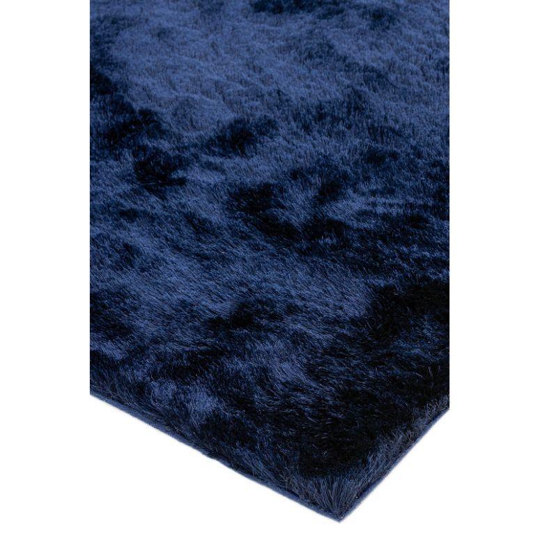 Dark blue shaggy rug with soft textured pile, close-up of corner and surface texture