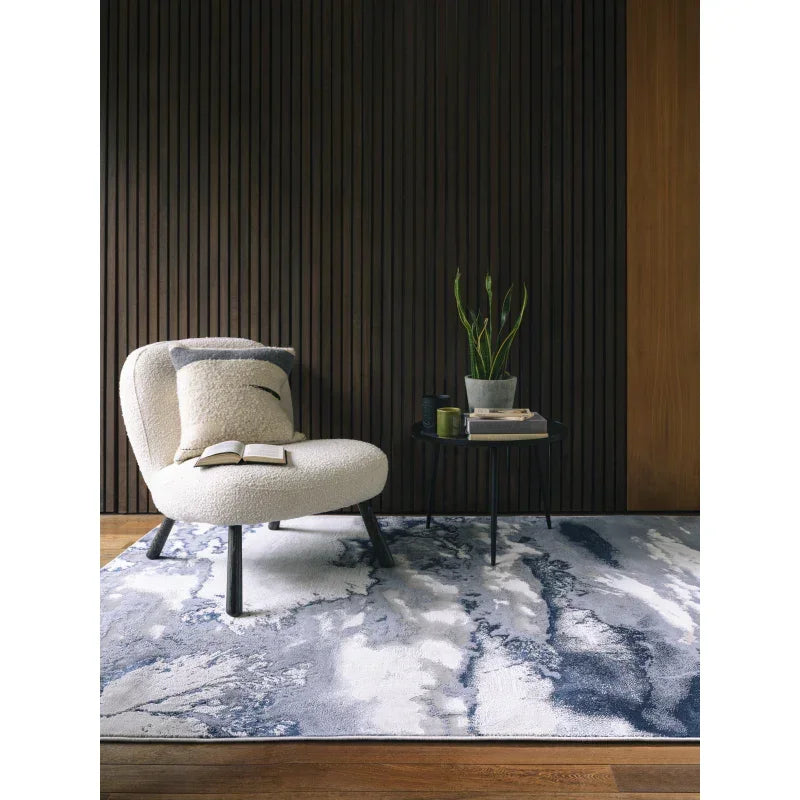 Modern accent chair and side table on abstract blue and white area rug in living room