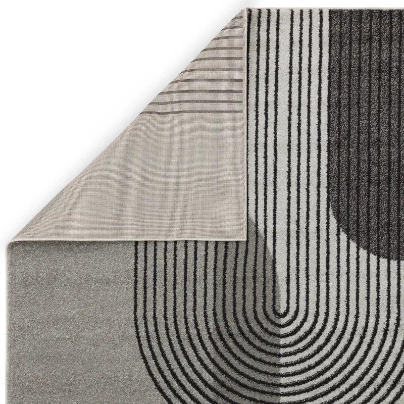 Modern grey and black area rug with curved line pattern, corner flipped to show backing
