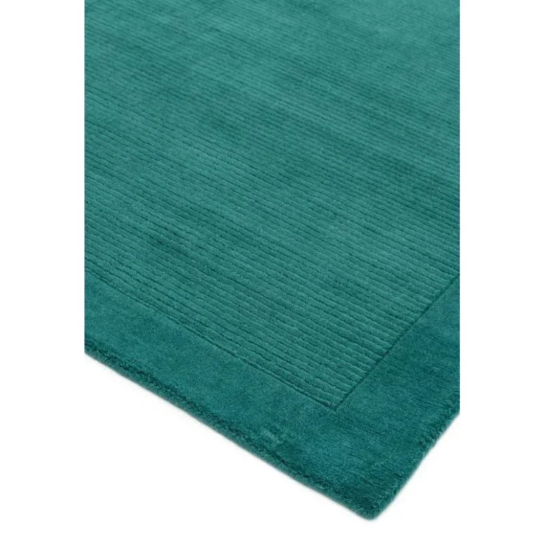 Teal area rug with textured ribbed pattern and solid border, corner detail view