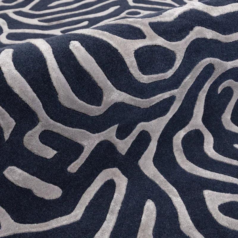 Closeup of modern area rug with raised grey abstract pattern on dark background