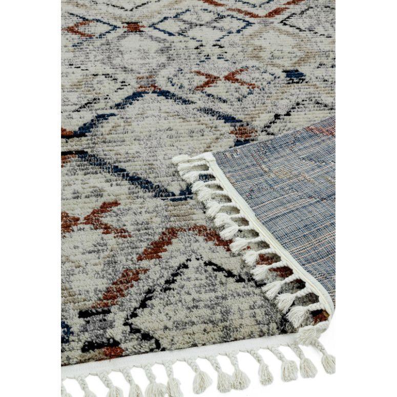Patterned rug with fringe detail, showing grey, navy, and rust geometric design and corner fold