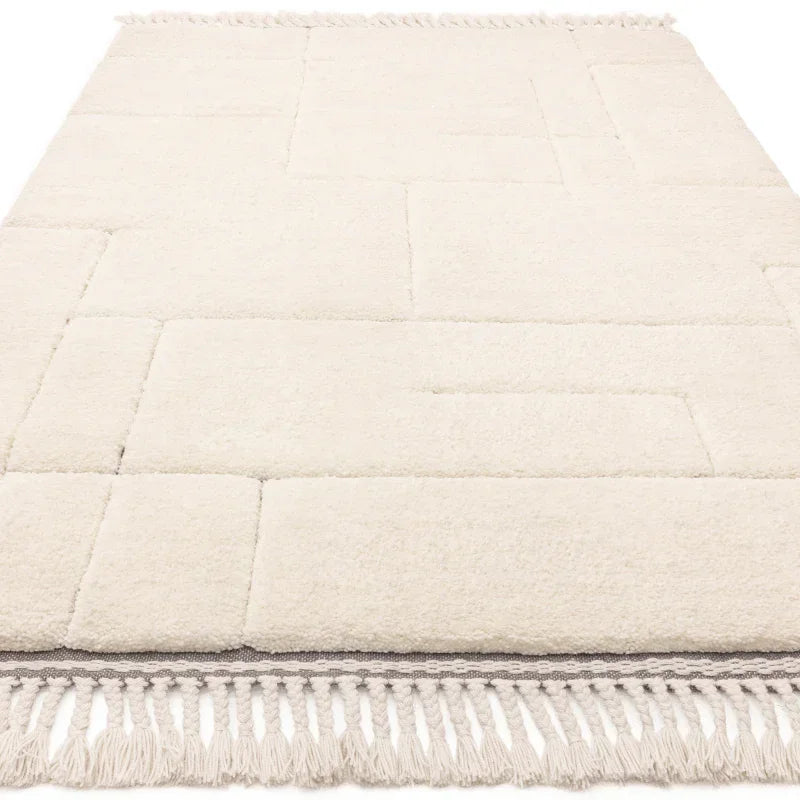 Cream area rug with geometric pattern and fringed edge closeup