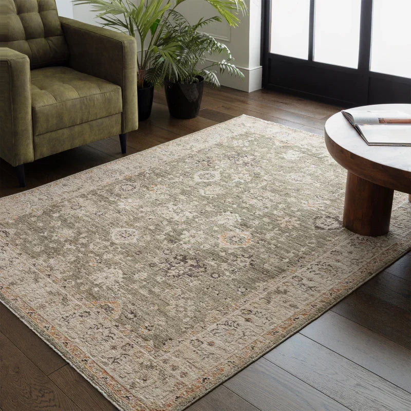 Traditional patterned area rug on hardwood floor with olive armchair and round wooden table